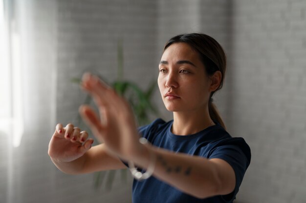 Mujer de tiro medio practicando tai chi en interiores