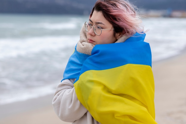 Mujer de tiro medio que se cubre con la bandera ucraniana