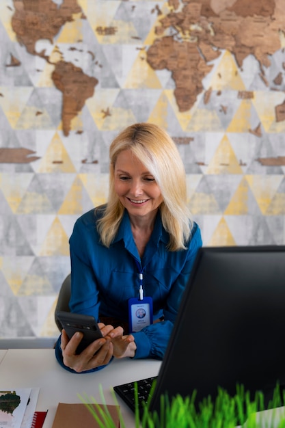 Foto gratuita mujer de tiro medio que trabaja en la oficina de una agencia de viajes.