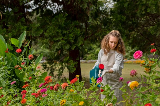 Mujer de tiro medio regando flores