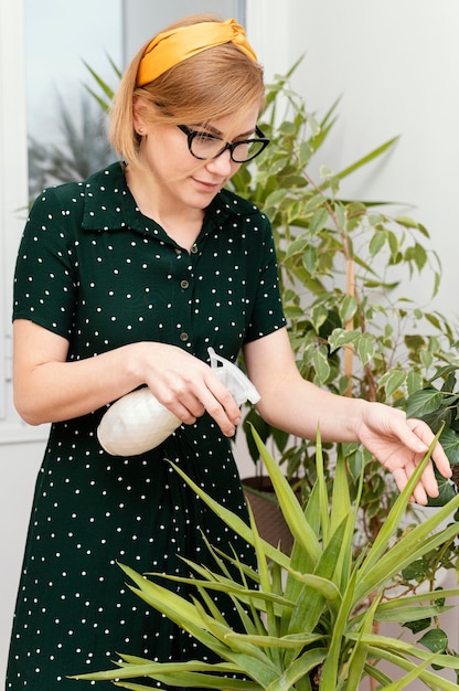 Mujer de tiro medio regando planta de interior