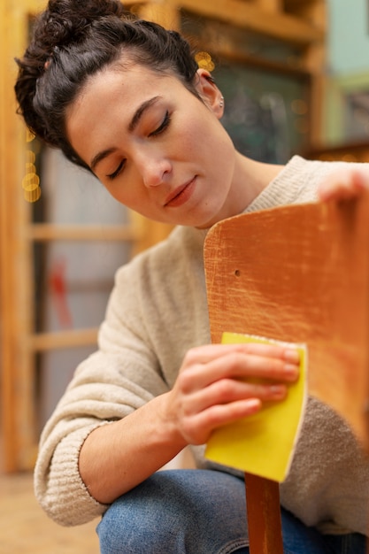 Mujer de tiro medio restaurando silla de madera.