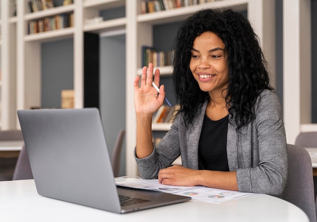 Mujer de tiro medio saludando a la computadora portátil