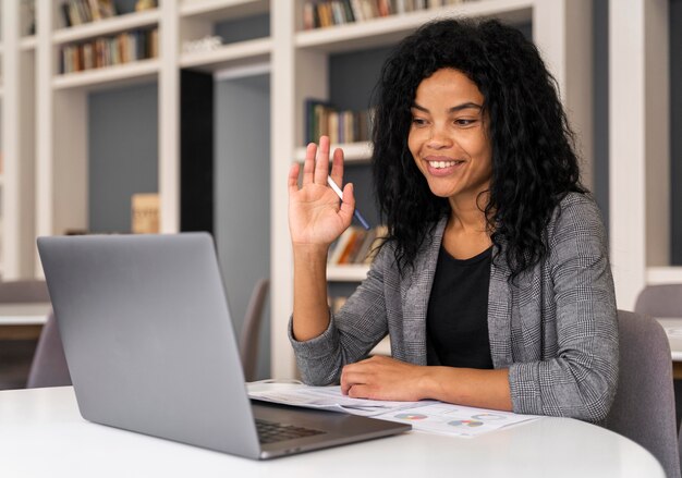 Mujer de tiro medio saludando a la computadora portátil