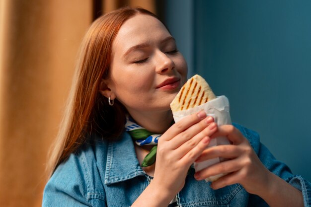 Mujer de tiro medio con sándwich envuelto en papel