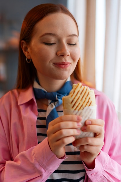 Mujer de tiro medio con sándwich envuelto en papel