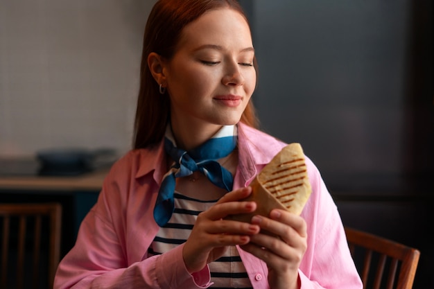 Mujer de tiro medio con sándwich envuelto en papel