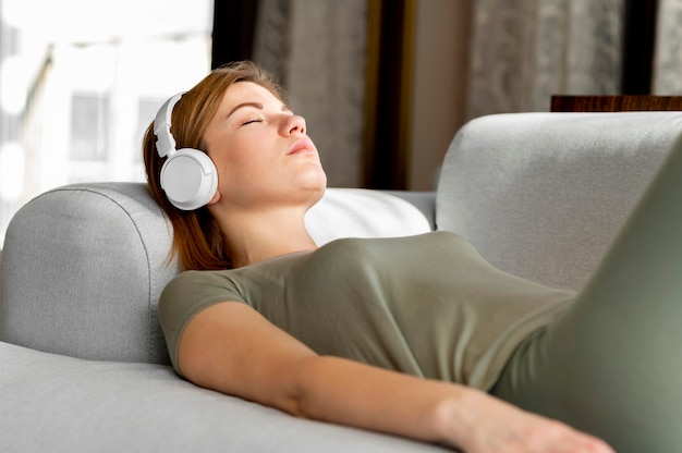 Mujer de tiro medio en el sofá con auriculares