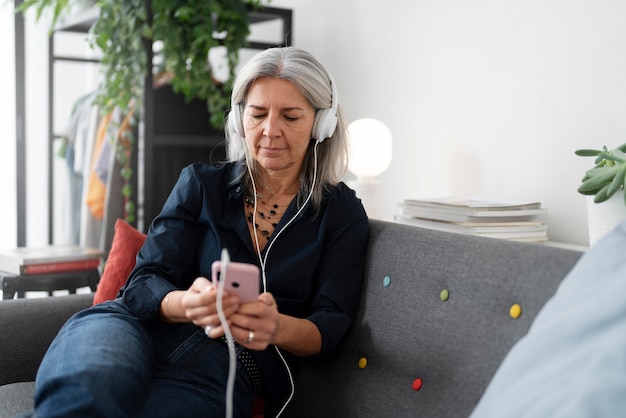 Foto gratuita mujer de tiro medio en el sofá con auriculares