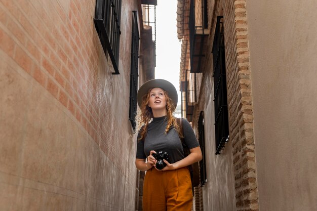 Mujer de tiro medio con sombrero y cámara