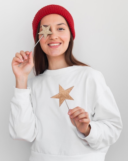 Mujer de tiro medio con sombrero sosteniendo decoraciones de estrellas