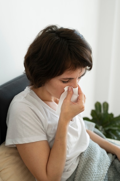 Mujer de tiro medio sonándose la nariz