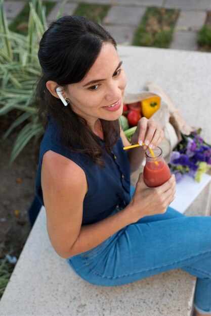 Mujer de tiro medio sosteniendo una botella de jugo