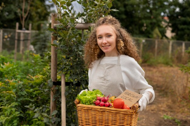 Mujer de tiro medio sosteniendo la cesta con verduras