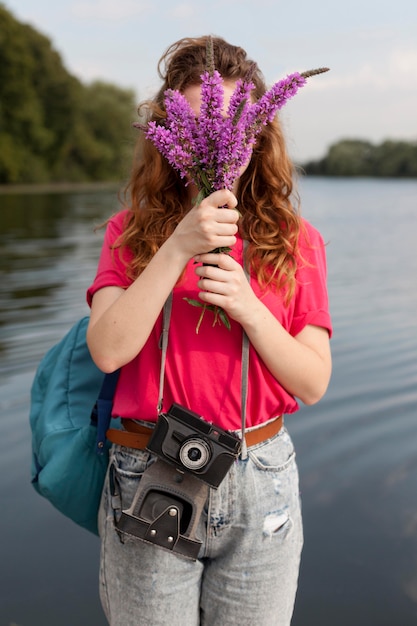 Foto gratuita mujer de tiro medio sosteniendo lavanda cerca del lago