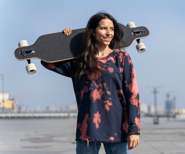 Mujer de tiro medio sosteniendo longboard