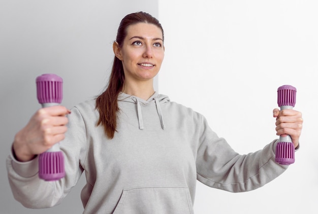 Mujer de tiro medio sosteniendo pesas