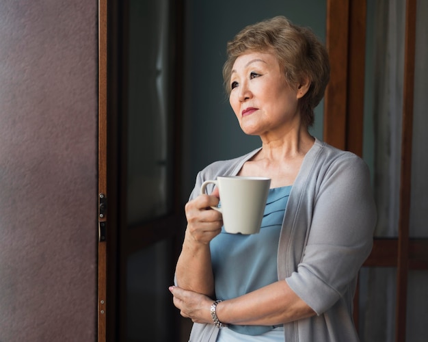 Mujer de tiro medio sosteniendo la taza de café