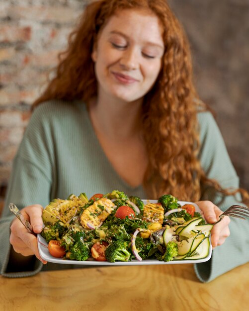 Mujer de tiro medio sujetando un plato con comida