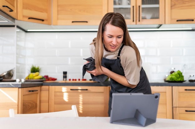 Mujer de tiro medio con tableta en la cocina