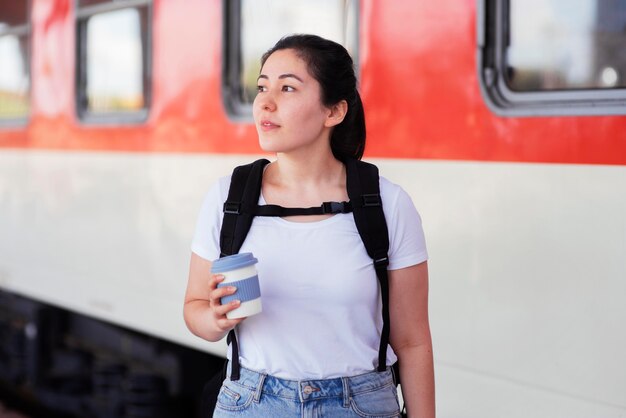 Mujer de tiro medio con taza en la estación de tren