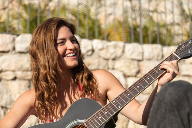 Mujer de tiro medio tocando la guitarra