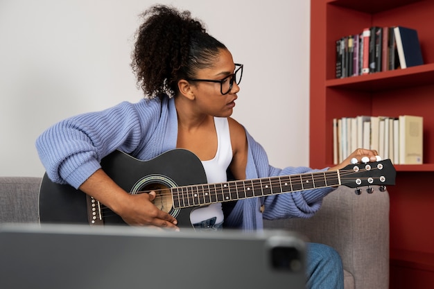 Foto gratuita mujer de tiro medio tocando la guitarra.