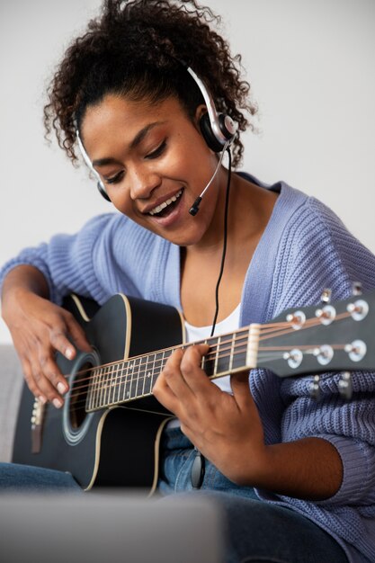 Mujer de tiro medio tocando la guitarra.