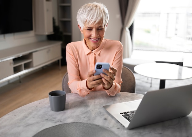 Mujer de tiro medio tomando un descanso con el teléfono inteligente