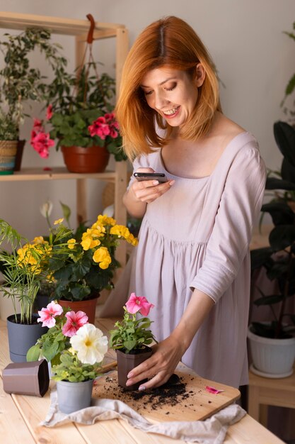 Mujer de tiro medio tomando fotos de la planta