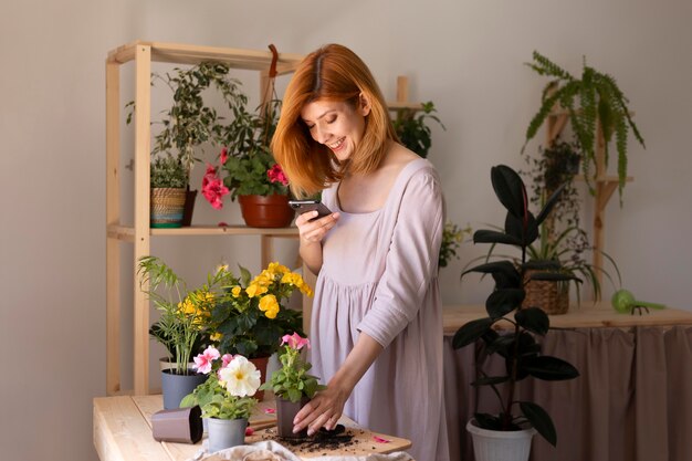 Mujer de tiro medio tomando fotos de la planta