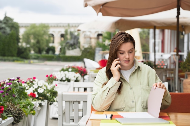 Mujer de tiro medio tomando notas en la terraza