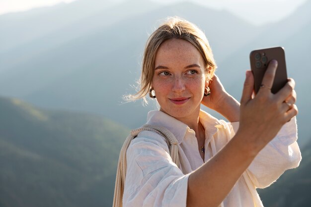 Mujer de tiro medio tomando selfie en la montaña