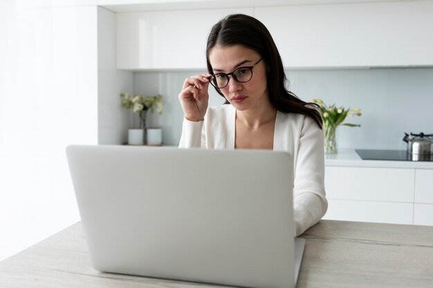 Mujer de tiro medio trabajando en una computadora portátil en casa