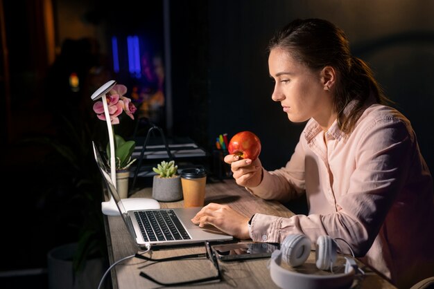 Mujer de tiro medio trabajando tarde en la noche