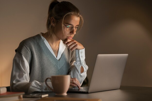 Mujer de tiro medio trabajando tarde en la noche