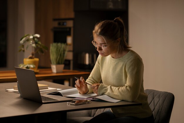 Mujer de tiro medio trabajando tarde en la noche