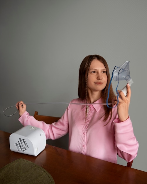 Mujer de tiro medio usando nebulizador en casa