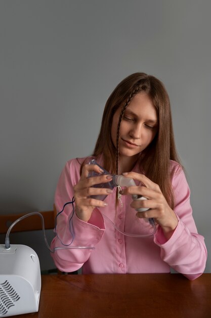 Mujer de tiro medio usando nebulizador en casa