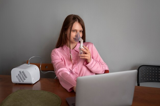 Mujer de tiro medio usando nebulizador en casa