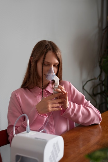 Foto gratuita mujer de tiro medio usando nebulizador en casa