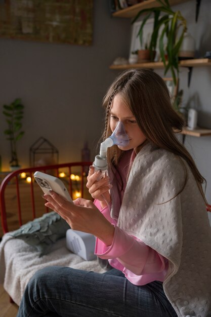 Mujer de tiro medio usando nebulizador en casa