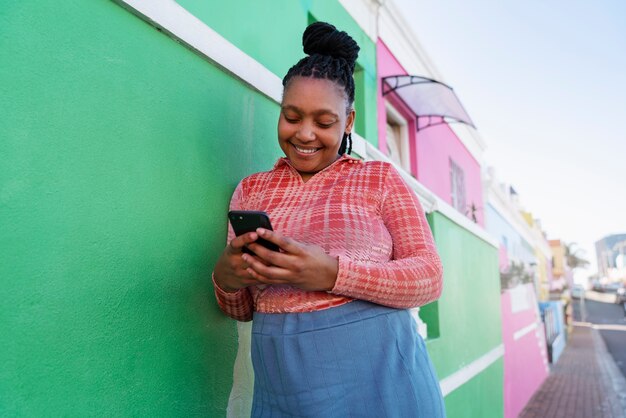 Mujer de tiro medio usando un teléfono inteligente al aire libre