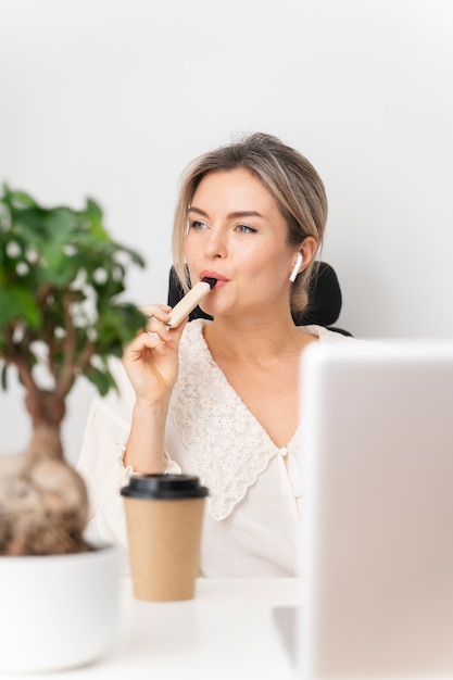 Foto gratuita mujer de tiro medio vapeando en el escritorio