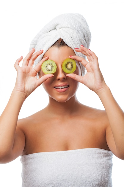 Mujer en toalla con kiwis en sus ojos