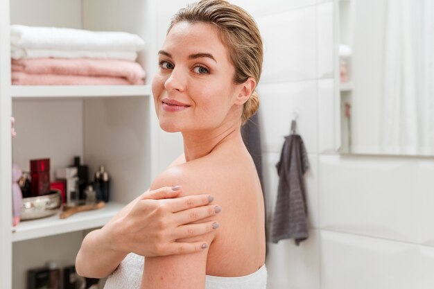 Mujer en toalla sosteniendo su brazo