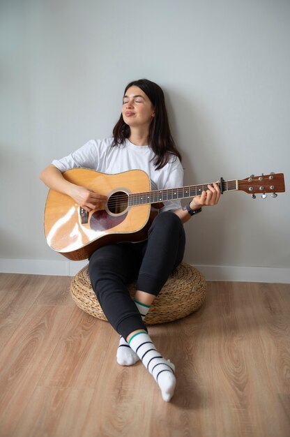 Mujer tocando la guitarra en casa durante la cuarentena