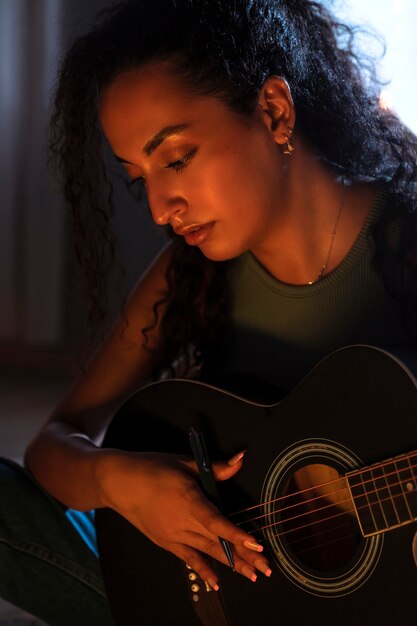 Mujer tocando la guitarra en casa vista lateral