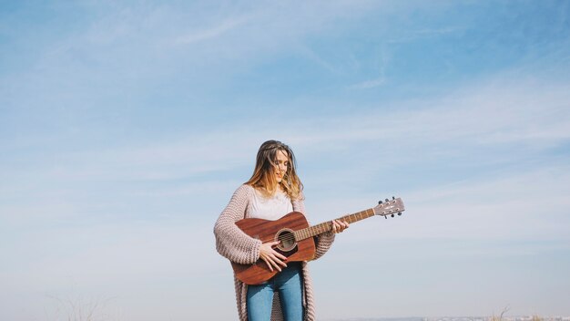 Mujer tocando la guitarra en la naturaleza
