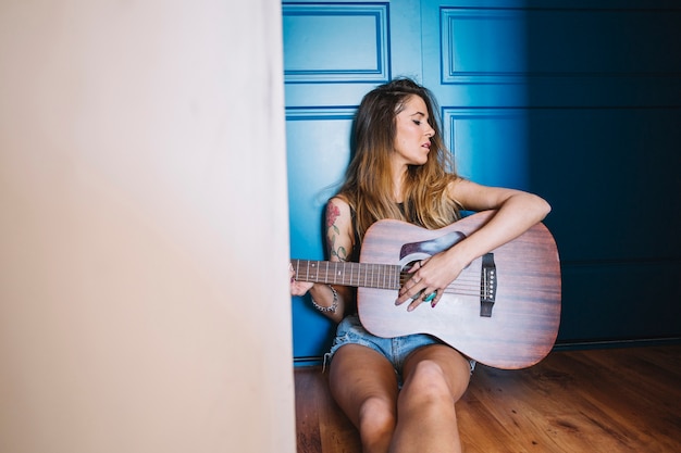 Mujer tocando la guitarra en el pasillo